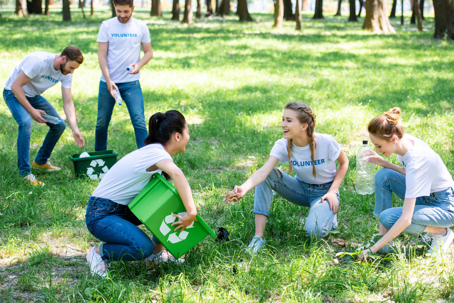 young volunteers with recycling boxes cleaning lawn in park
